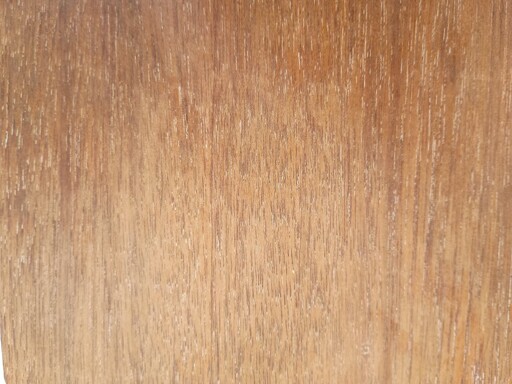 Brown wood surface with visible grain. Traces of white paint within grain.