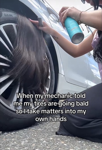 Picture of a car tire with a wig set on top and a person arms styling it with the caption, “When my mechanic told me my tires are going bald so I take matters into my own hands”