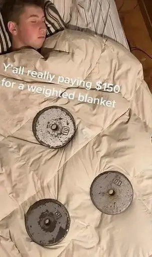 a person sleeping under a blanket with 3 metal weights placed on top of it. Caption: "Y'all really paying $150 for a weighted blanket".